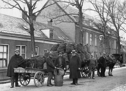 53942 Afbeelding van werklui bij een kolenwagen met daar achter een handkar met weegschaal op de Blauwkapelseweg te Utrecht.
